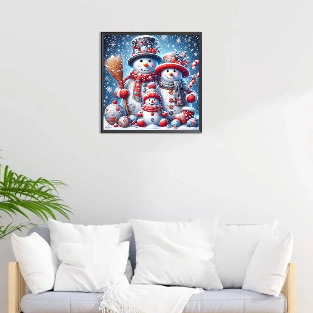 Framed diamond painting artwork of snowmen on a wall above a white sofa with decorative pillows.