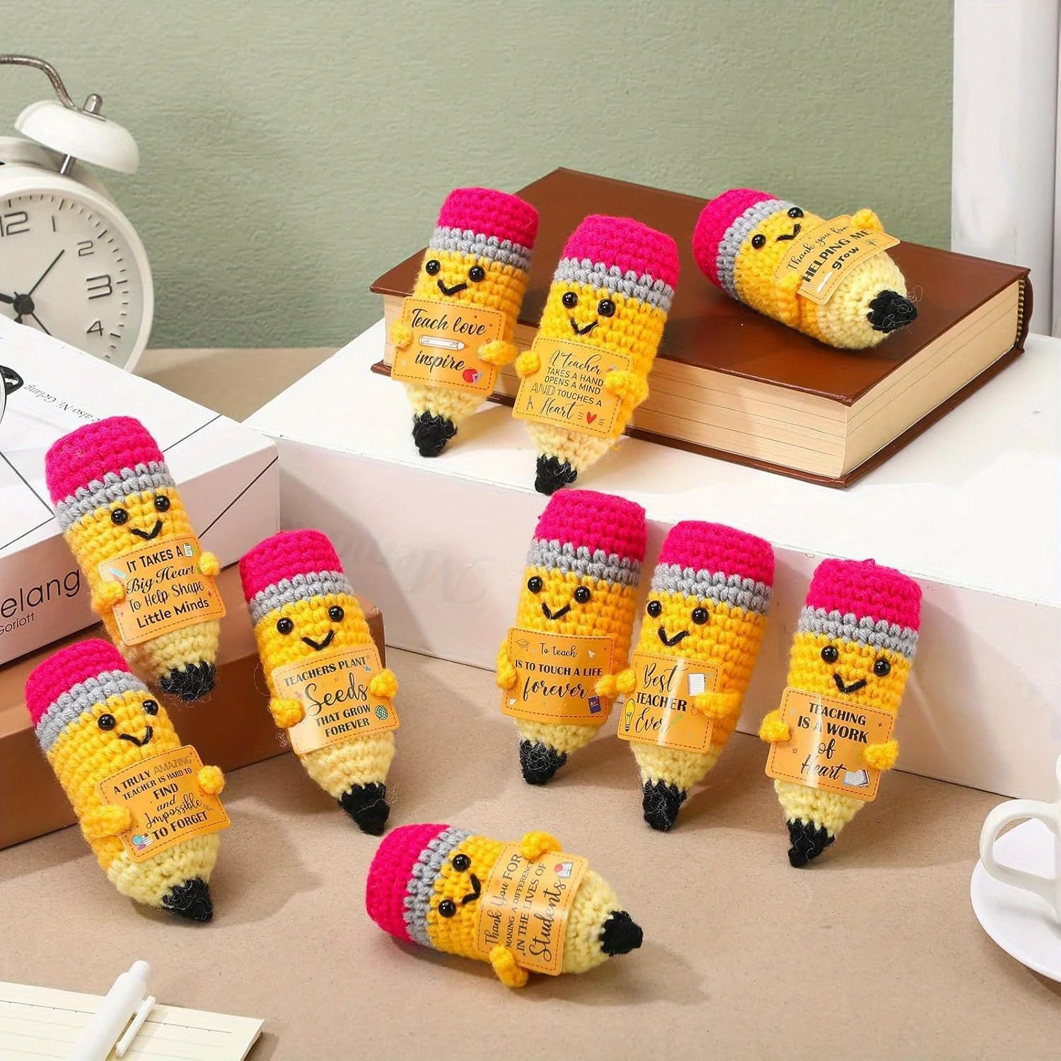 Set of crochet pencil-shaped toys with smiling faces on a desk.