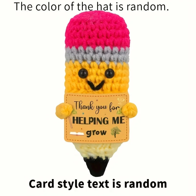 Crocheted pencil-shaped plush toy with a pink top, yellow body, and gray middle section, holding a sign that says 'Thank you for helping me grow'.