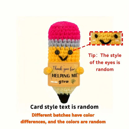 Crocheted pencil-shaped toy with a pink top and yellow body, featuring text and a smiley face.