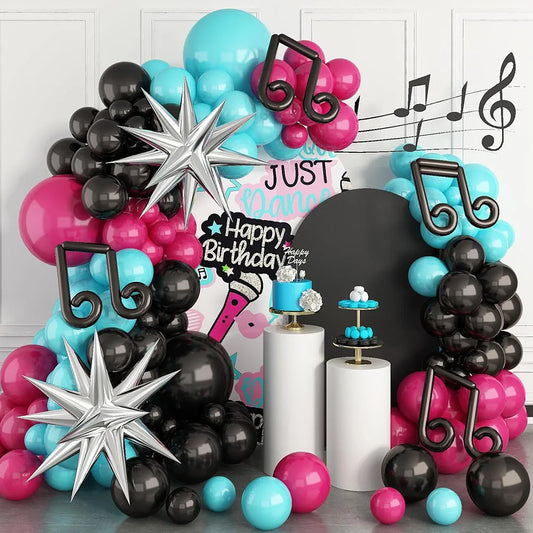 Colorful balloon arch with musical notes and birthday decorations on a white wall.