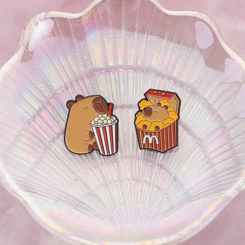 Two cartoon-style Capybara pins popcorn