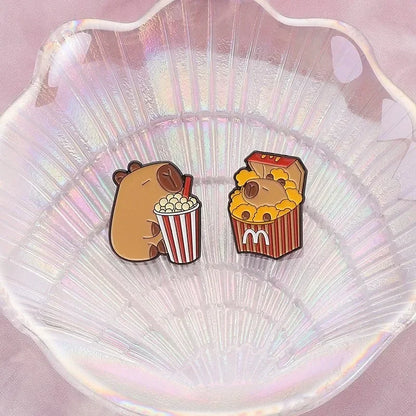 Two cartoon-style Capybara pins popcorn
