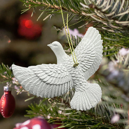 White dove ornament hanging on a Christmas tree with blurred red ornaments in the background.