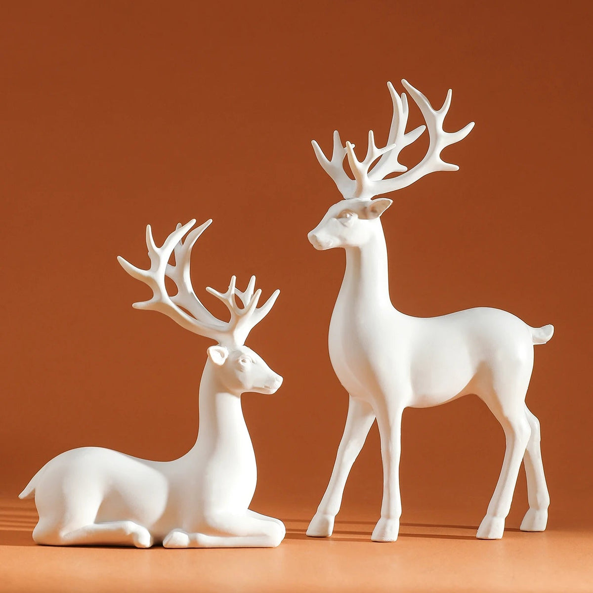 Two white deer figurines on a brown background