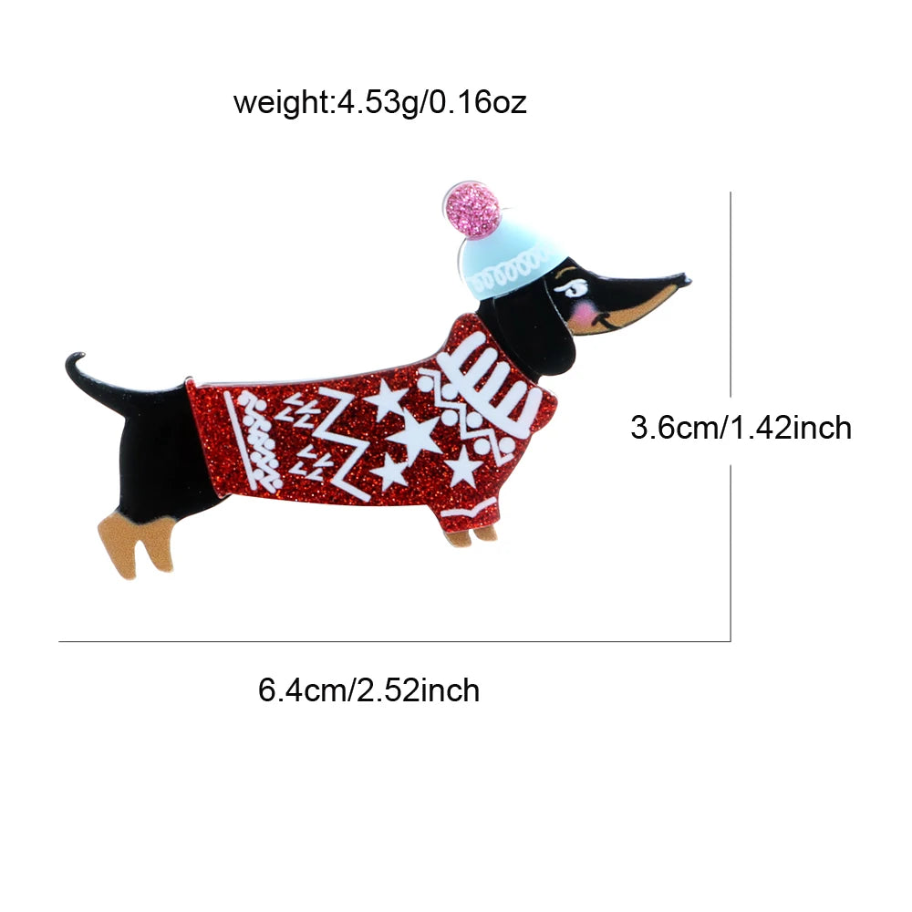 A dachshund-shaped decorative pin or charm wearing a red glitter sweater with white stars and stripes, a light blue hat, and pink pom-poms, shown with measurement lines and text indicating weight 4.53g/0.