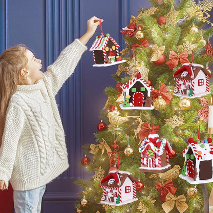Child decorating a Christmas tree with gingerbread house ornaments against a blue wall.