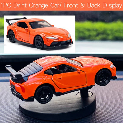 Orange toy car on a rotating stand with a scenic background